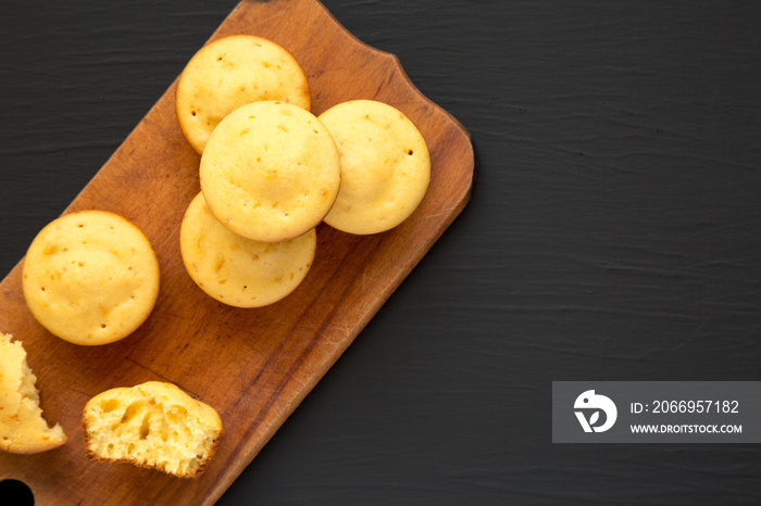 Homemade Cornbread Muffins on a rustic wooden board on a black surface, top view. Flat lay, overhead, from above. Space for text.