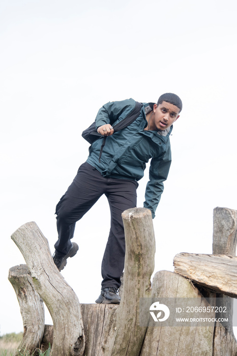 Portrait of man with backpack balancing on old wooden posts