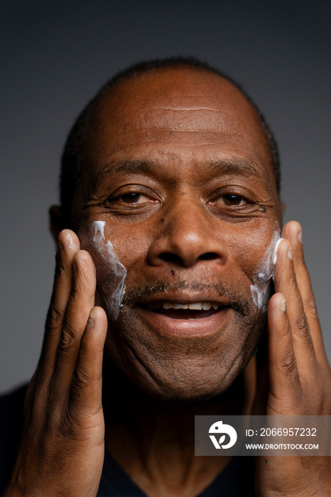 Portrait of man applying cream on face