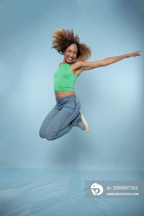 Smiling woman jumping in studio