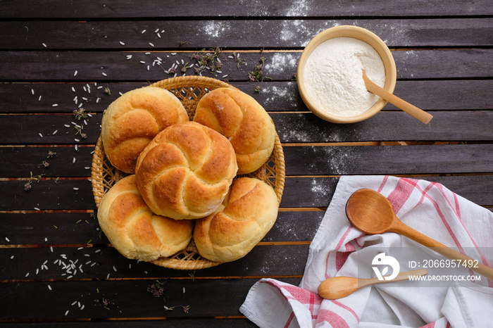 Tasty Kaiser rolls in a wicker basket on a wooden table