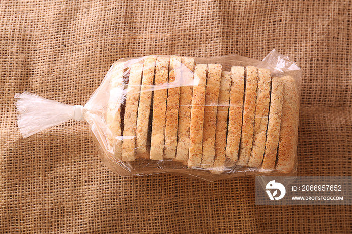 Sliced bread in plastic bag on sackcloth, top view