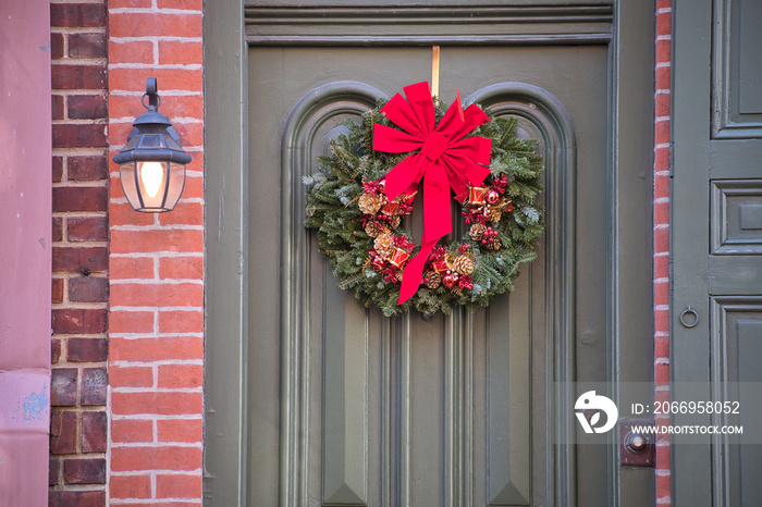 Large christmas wreath and red bow grace the ornamental front door of historic home