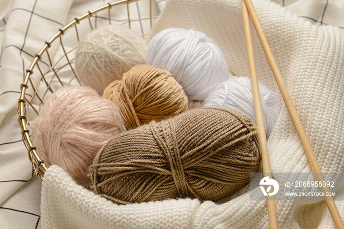 Basket with knitting yarn and needles on fabric background, closeup