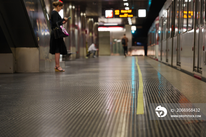 Low angle and selected focus view at yellow tape line lie in front of tram on platform underground railway station in Germany during social distancing by epidemic of COVID-19.