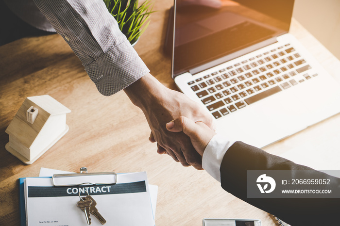 Top view hands of agent and client shaking hands after signed contract buy new apartment.