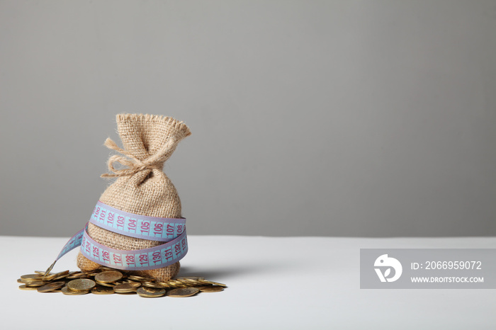 Bag with money and measuring tape on gold coins. Lack of money, poverty and savings.