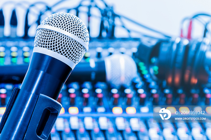 Microphone on tripod with mixer background in sound control room.