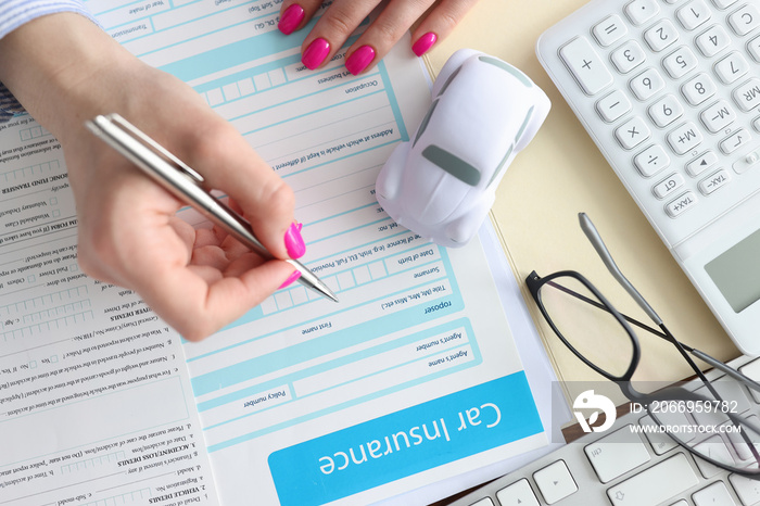 Agent filling out car insurance form with ballpoint pen closeup