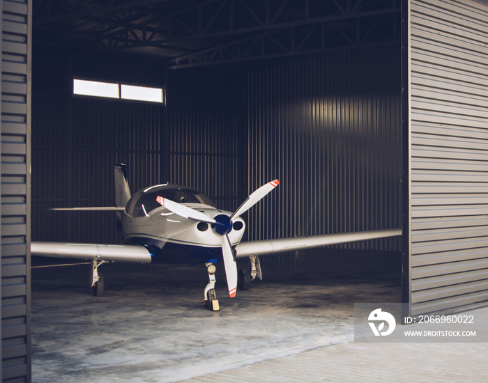 Small white private jet parked in the hangar