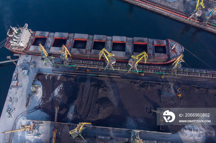 Loading coal mining in port on cargo tanker ship with crane bucket of train. Aerial top view