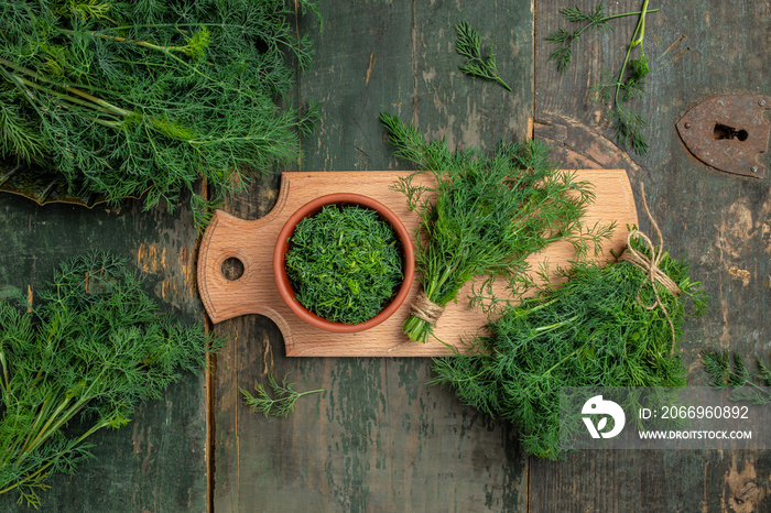 Chopped fresh dill on a cutting Board and a bunch of dill preparation for freezing serving size organic healthy ething natural product portion on a wooden table. Top view