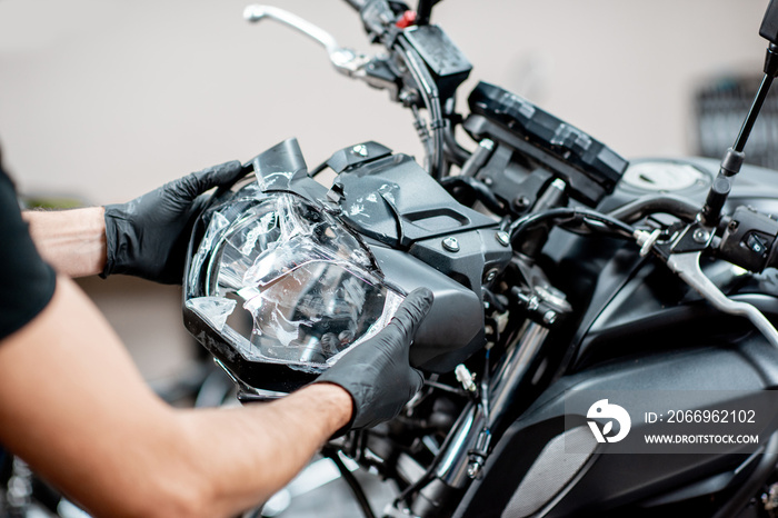 Worker repairing motorcycle headlight in the workshop