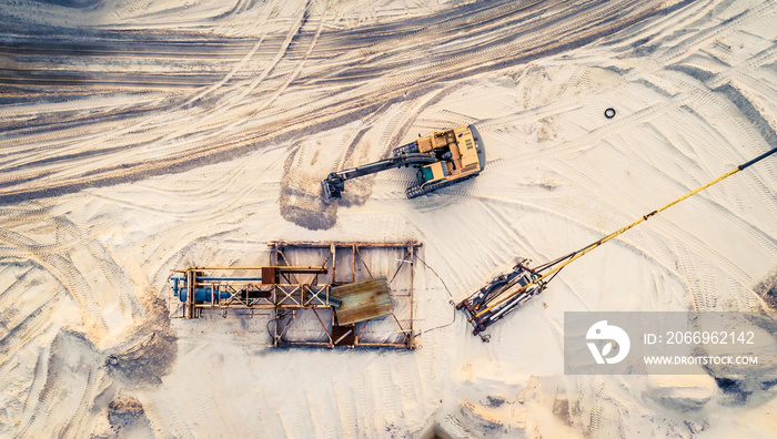 Aerial view of machinery and mine equipment near road on sandy surface