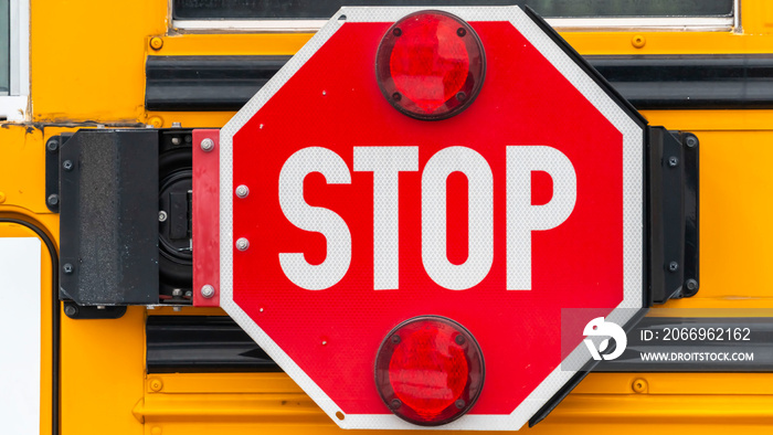 Panorama Close up of an octagon shaped red stop sign with signal lights on a school bus