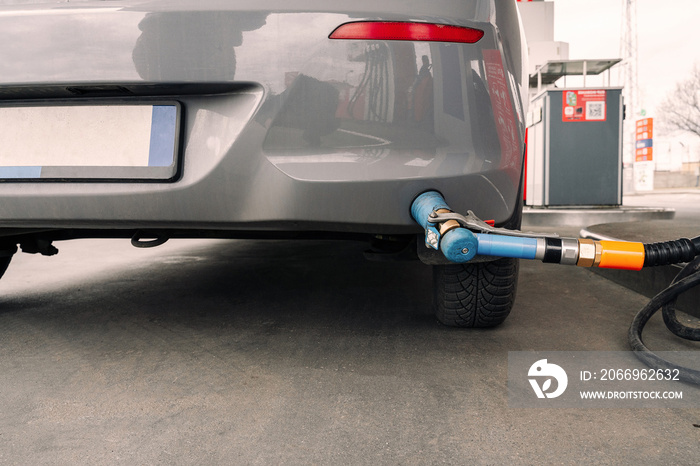 Person pumping gas. Fuel petrol for car at gasoline oil station nozzle in tank. Hand and black refueling gun close-up.