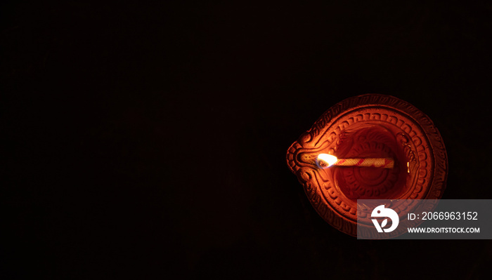 Happy Diwali. Diya oil lamp against dark background, top view,