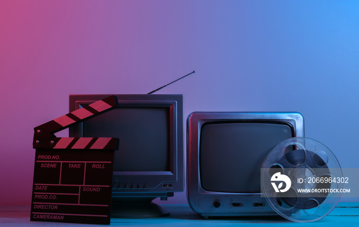 Old tv receivers with movie clapperboard, film reel in red blue neon light. Entertainment Industry, Media 80s