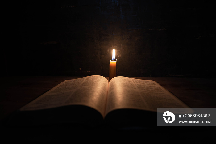 Bible and candle on a old oak wooden table.