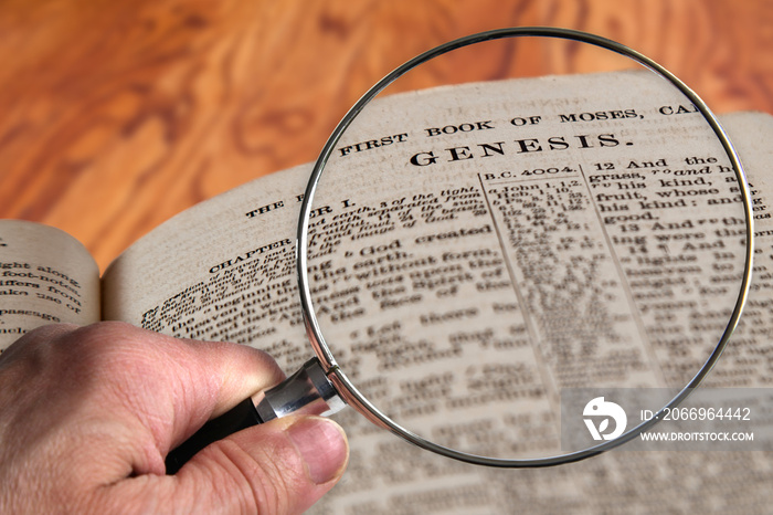 Magnifying Glass on Famous Bible Chapter Genesis, a King James Bible which is Public Domain.