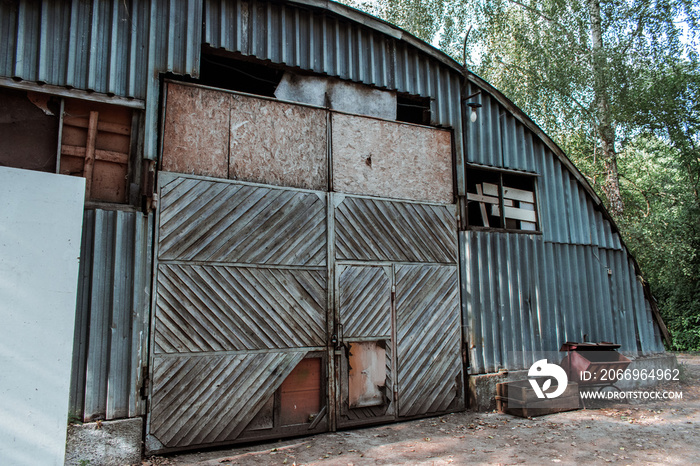 Old abandoned hangar with a wooden gate. Facade of an old hangar