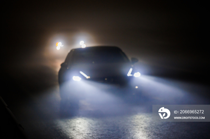 two blurred cars moving on empty night foggy road