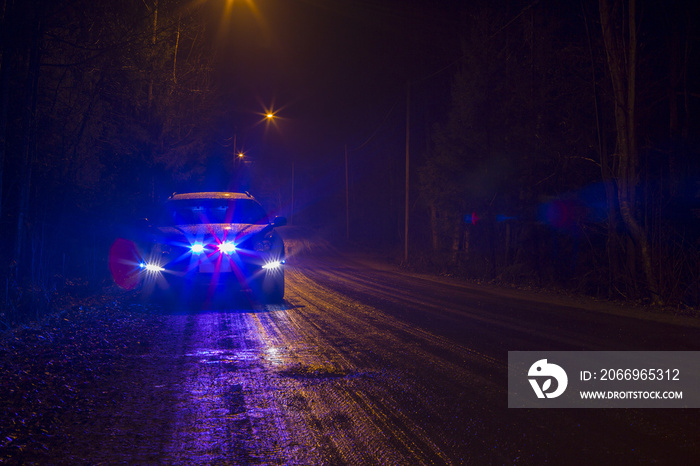 Police car is pulling a driver down on a dark and rainy road. Flashing lights and sirens. Bad condition to drive. Dark night. Flare effect applied.