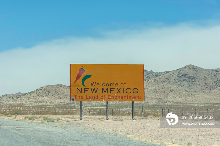 AZ, USA – June 14, 2011 – A bright yellow Welcome to New Mexico road sign sits on the side of the road in Arizona.