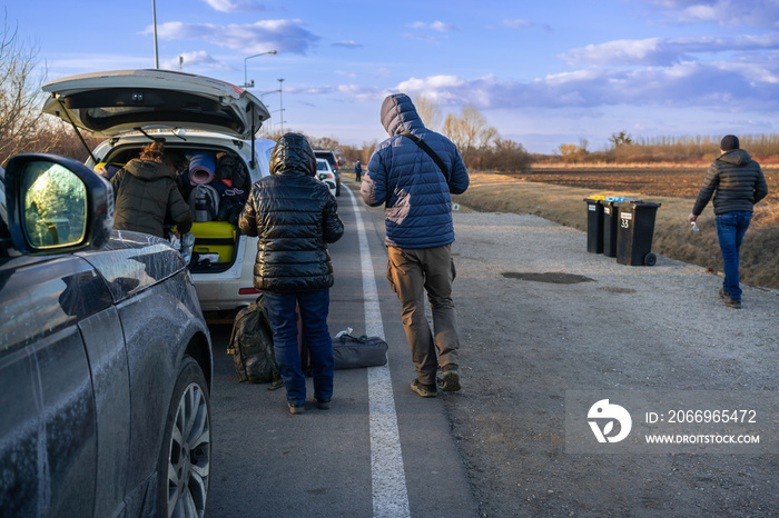 Refugees from Ukraine, next to the open trunk of a car, carry hot tea in a convoy of cars in front of the checkpoint from Romania to Hungary.