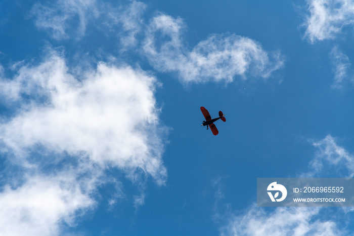 Biplane View from Below with Scattered Clouds