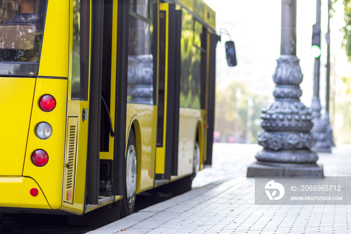 Modern yellow city bus with open doors at bus station