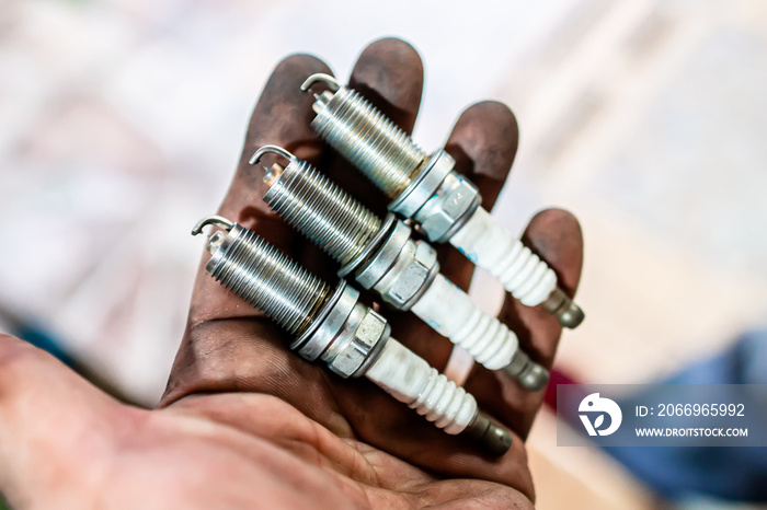 Old spark plug It has been in use for many years. On the black oil smeared hands.