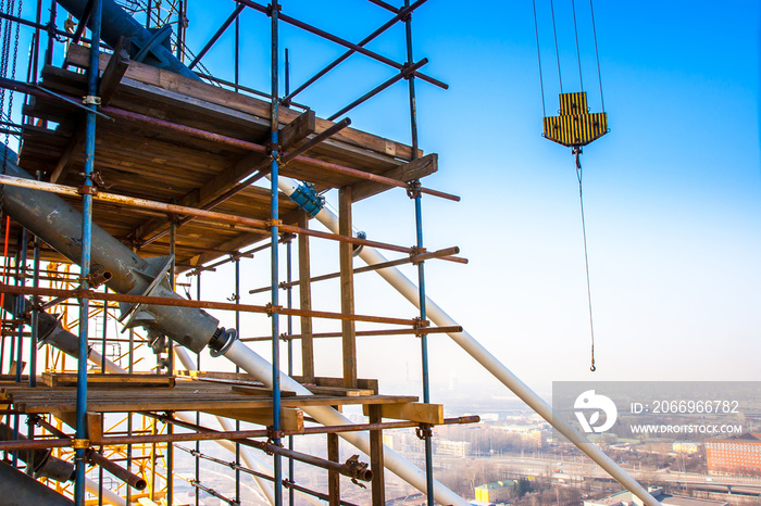 Scaffolding at altitude. High-altitude work. Crane hook. Lifting of building materials.