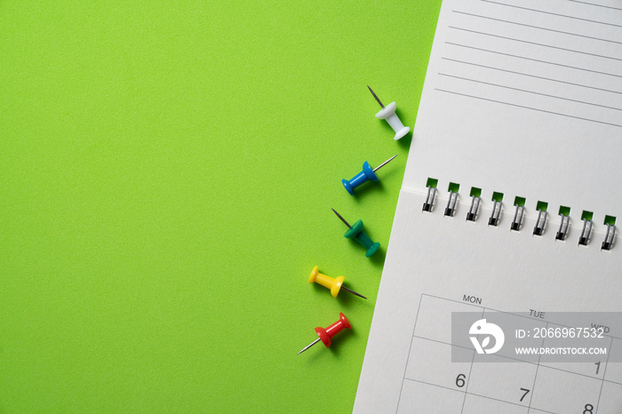 close up of calendar and pin on the green table background, planning for business meeting or travel planning concept