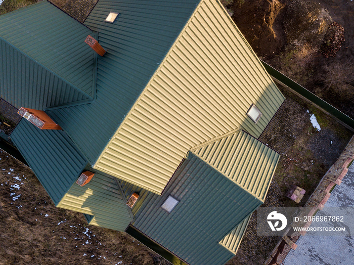 Aerial view of new residential house cottage with shingle roof on fenced yard on sunny day.