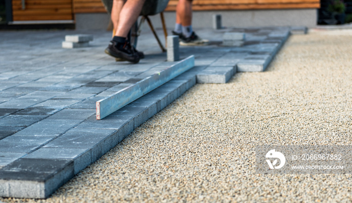 Laying gray concrete paving slabs in house courtyard driveway patio.