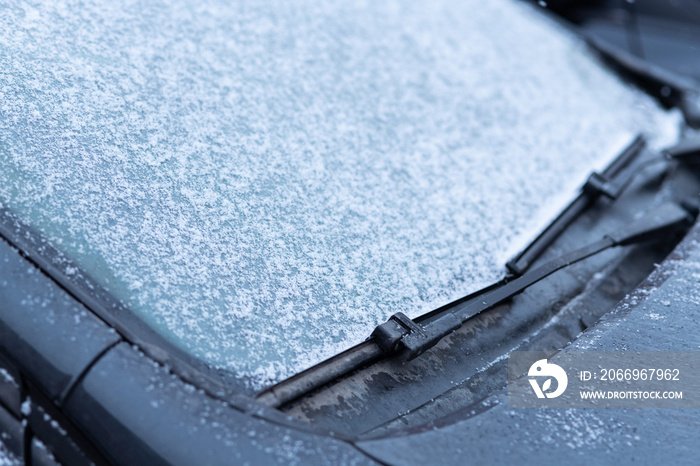 Snow covered car window with wipers, macro, close up. Antifreeze was not used. Vehicles in snow. Winter time is coming. Bad weather conditions