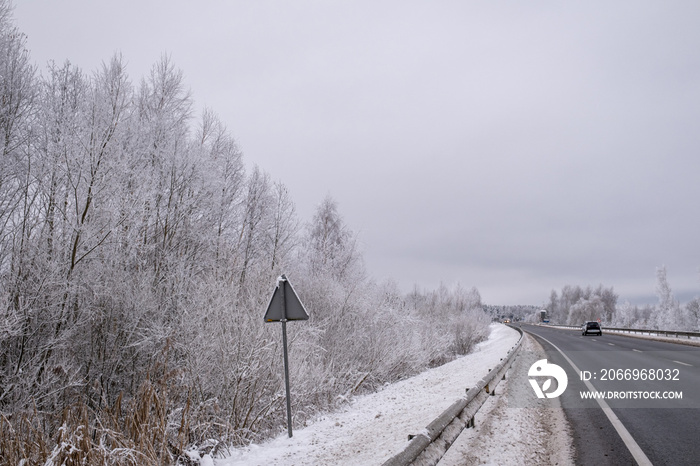 clean smooth winding asphalt road through snow covered fields and forests in Latvia near Jelgava town