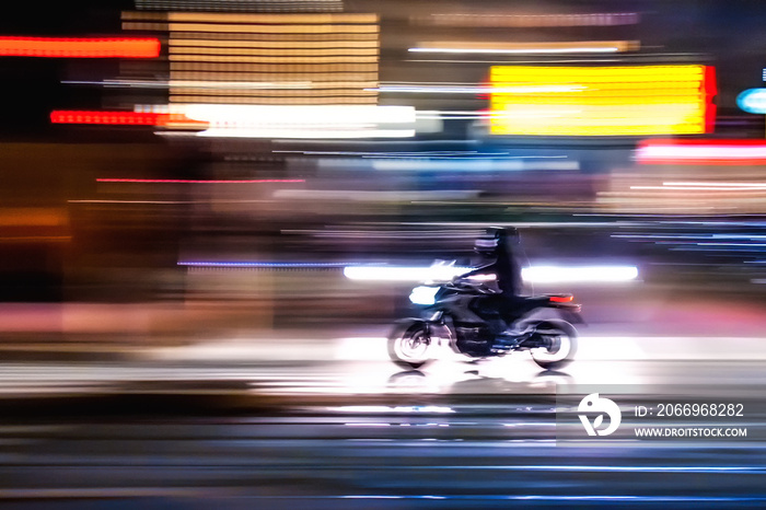 Motocicletta che sfreccia veloce di notte per le vie con luci colorate di una  grande città metropolitana