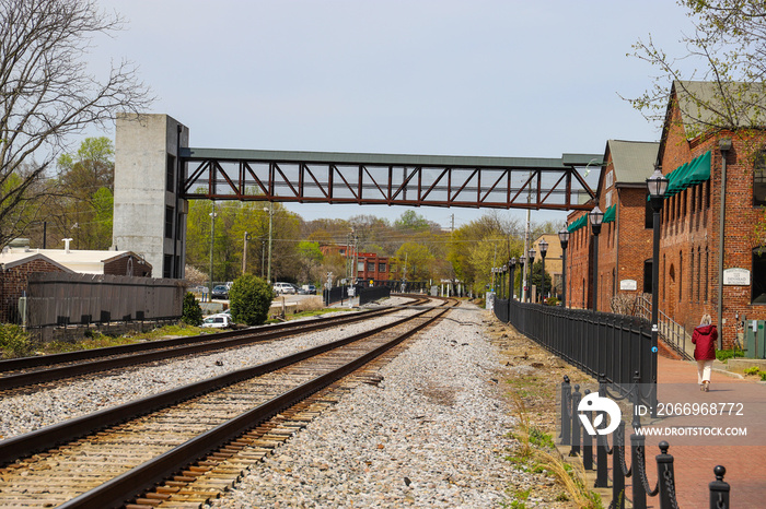 railroad tracks covered in gravel with lush green grass on the edges and red brick buildings along the tracks with blue sky and powerful clouds at the Marietta Square in Marietta Georgia USA