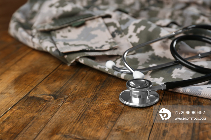 Stethoscope and military uniform on wooden background