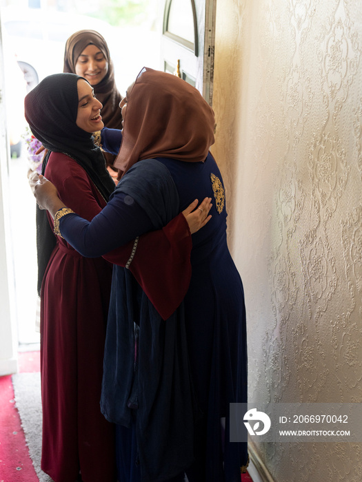 Women greeting guests visiting for Ramadan at home