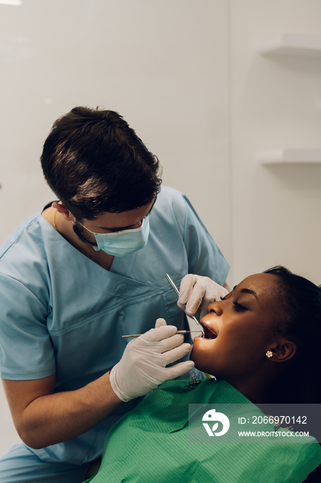 Dentist providing dental care treatment to a african american female patient