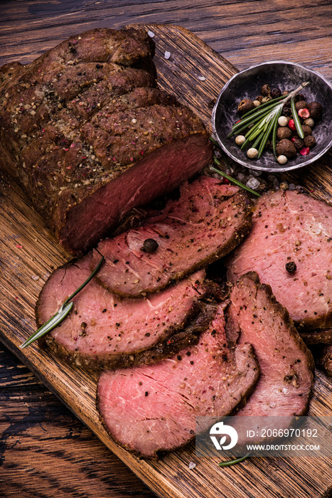 Roast beef on cutting board with salt and pepper. Top view.