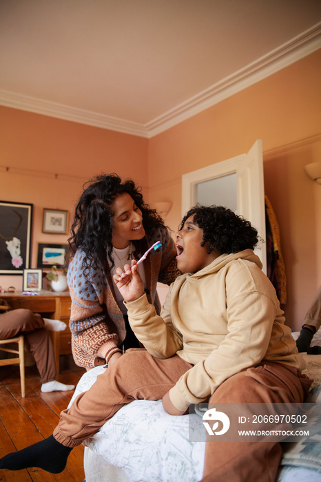 Mid-sized mother helping her son brush his teeth