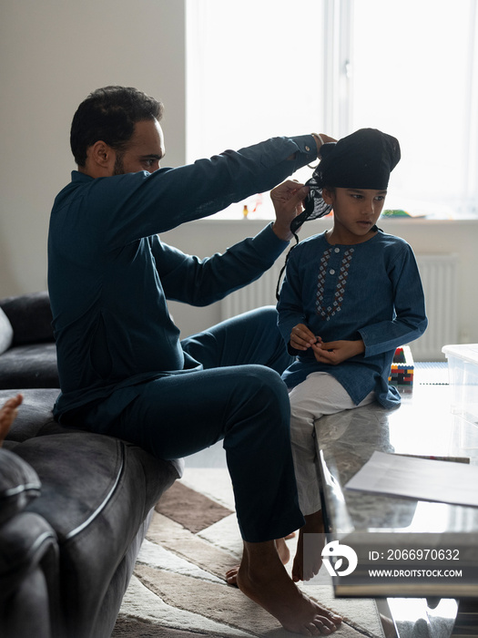 Father wrapping turban around son’s head (6-7)