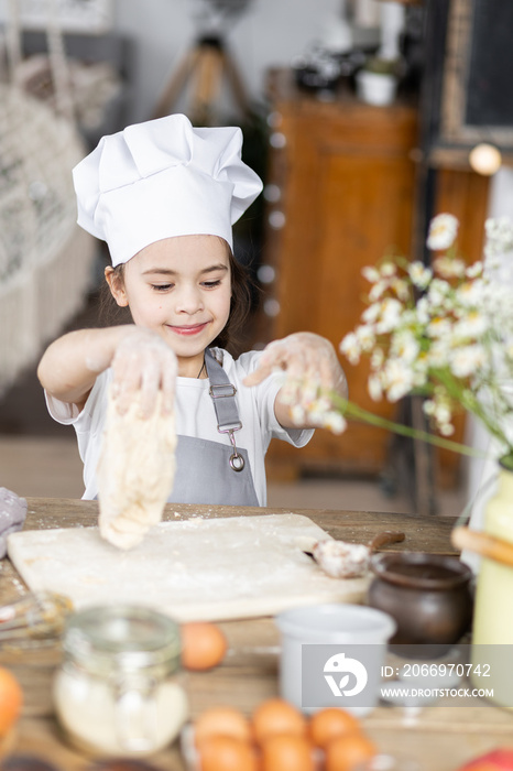 Cute little girl baking homemade sweet pie together, having fun. Home bakery, little kids in process of food preparation in the kitchen at home, helping mother, doing chores