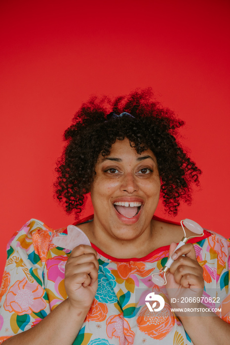 close up of a plus size black person smiling holding skin care tools