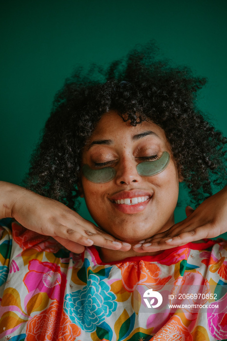 closeup of a plus size black person practicing skin care smiling eyes closed