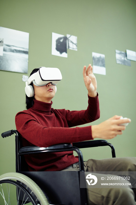 Young Asian man with disability wearing VR headset visiting contemporary photography exhibition in modern art gallery using augmented reality technology